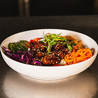 Bites of hoisin BBQ filet tips on lemon-herb rice, sesame red cabbage, smoked pineapple, pickled carrots, fresnos, cucumber, hazelnut dukkah from Max Dales Steak and Chop House