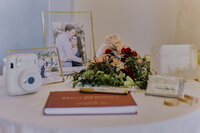Wedding reception table with framed pictures and a guestbook
