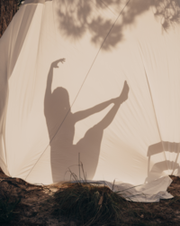 Woman creating dancing shadows onto a white tent