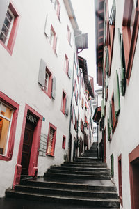 Narrow passageway of white buildings with colorful accents in Basel, Switzerland