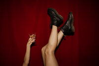 Feet in the hair with a hand holding up a drink 