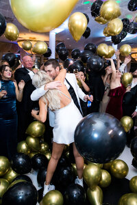 Image of bride and groom dancing at reception surrounded by balloons