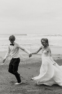 Bride and groom running along Ruby Beach after their elopement in Olympic National Park.