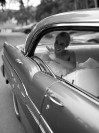 Black and white image of bride in the backseat of a car