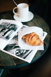 A mug with a croissant and a photography book.