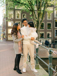 Parents cuddle daughter on the Negen Straatjes in Amsterdam during a photoshoot.