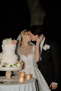 Bride and Groom share a kiss in front of their wedding cake. 