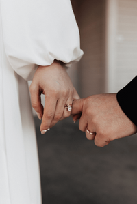 The groom and the bride are holding pinkies