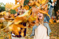 Two people throwing fall leaves