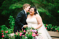 A wedding couple laughing while holding wedding bouquet