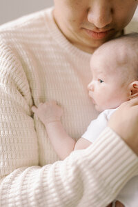 Dad holding his newborn baby on his chest.