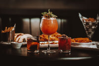 Appetizing spread featuring loaded nachos, crispy fries with dipping sauce, and colorful cocktails, perfect for sharing during a fun night out.