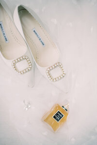 Bridal flat lay with white Manolo Blahnik designer heels and vintage Chanel perfume