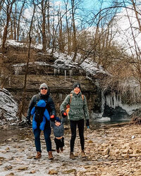 A family strolls through the woods by a waterfall at Quarry Trails in Columbus, Ohio.
