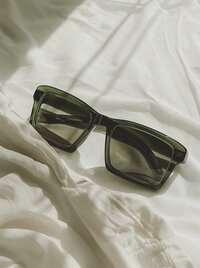oversized green acrylic sunglasses on white fabric