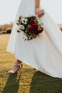 A bride holds a lush floral bouquet in golden sunlight, showcasing the elegance of editorial and cinematic wedding photography by TM Photo Co.