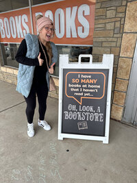 Jennifer Mosier. photographer and book lover, posing with a book themed sign