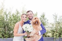 Bride and groom holding dog