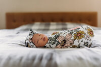 newborn baby in New Jersey home is wrapped up in a swaddle on their bed asleep and peacefully captured. This image is part of the session flow Little Leaves Photography teaches in her in-home lifestyle newborn education series.
