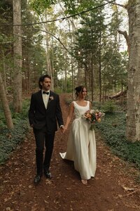 bride and groom walk through woods on wedding day