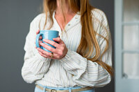 Close-up of a woman holding a blue ceramic mug, symbolizing quiet moments and deeper conversations from the Big Talk portrait and story series.