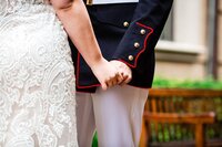 Close up photo of bride and military groom holding hands
