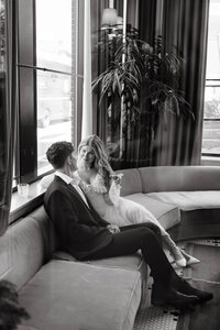 Bride and groom sitting on a couch while smiling at each other