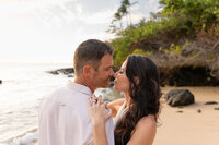 Maui Family Photographer captures couple kissing during Maui family photos on beach