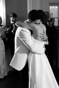 Couple in wedding attire kiss during their first dance