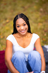 High school senior girl sitting on a blanket outdoors.