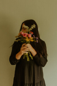 woman holding floral bouquet in front of face