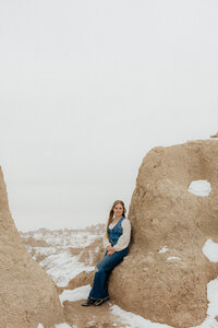 A woman leaning against a rock formation.