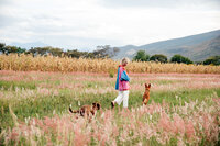 Sasha leading two dogs on a walk through the field on the farm