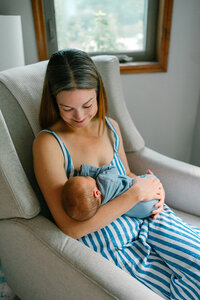 A parent sitting in a chair holding a newborn
