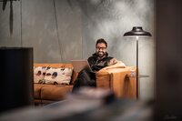 miljöbild av coworkingyta, leende man i soffa