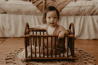 a baby boy sitting in a wooden crib in rochester ny