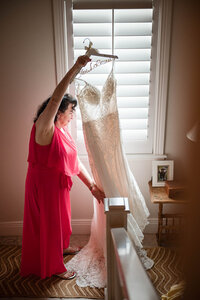 Bride preparing for her luxury San Antonio wedding by hanging her dress in a window, captured by CMH Studios.