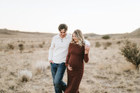 Husband and wife walking in the desert during their maternity session.