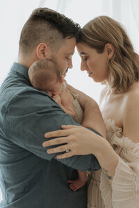 Newborn baby cradled in loving hands during an intimate indoor session in Perth