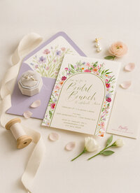 Lavender and floral bridal shower invitation suite with matching envelope liner, styled with ribbon, florals, and soft feminine details