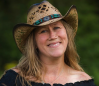 Woman in a cowboy hat smiling outside