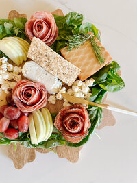 a charcuterie board with meat slices arranged into rose shapes
