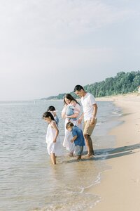 Katelyn and Daniel Ng stand on a beach with their four children looking at the waves.