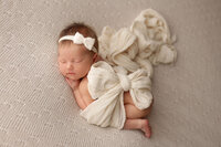 newborn baby girl sleeping on a white blanket