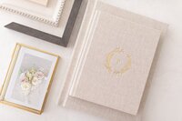 A luxury heirloom linen album sits next to custom frame corners and a glass proof box with artwork by Melissa Mayrie Photography, a Charlotte photographer