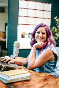 Photography Coaching | Karinda K | Karinda on her desk smiling with a microphone