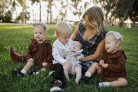 A picture of a mother with her four little children sitting on the grass posing for a candid photo