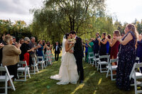 Bride and groom share a kiss walking down the aisle