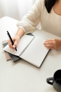 close up of woman working at desk writing in notebook