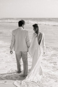 Couple walks down the beach during their Mexico wedding.